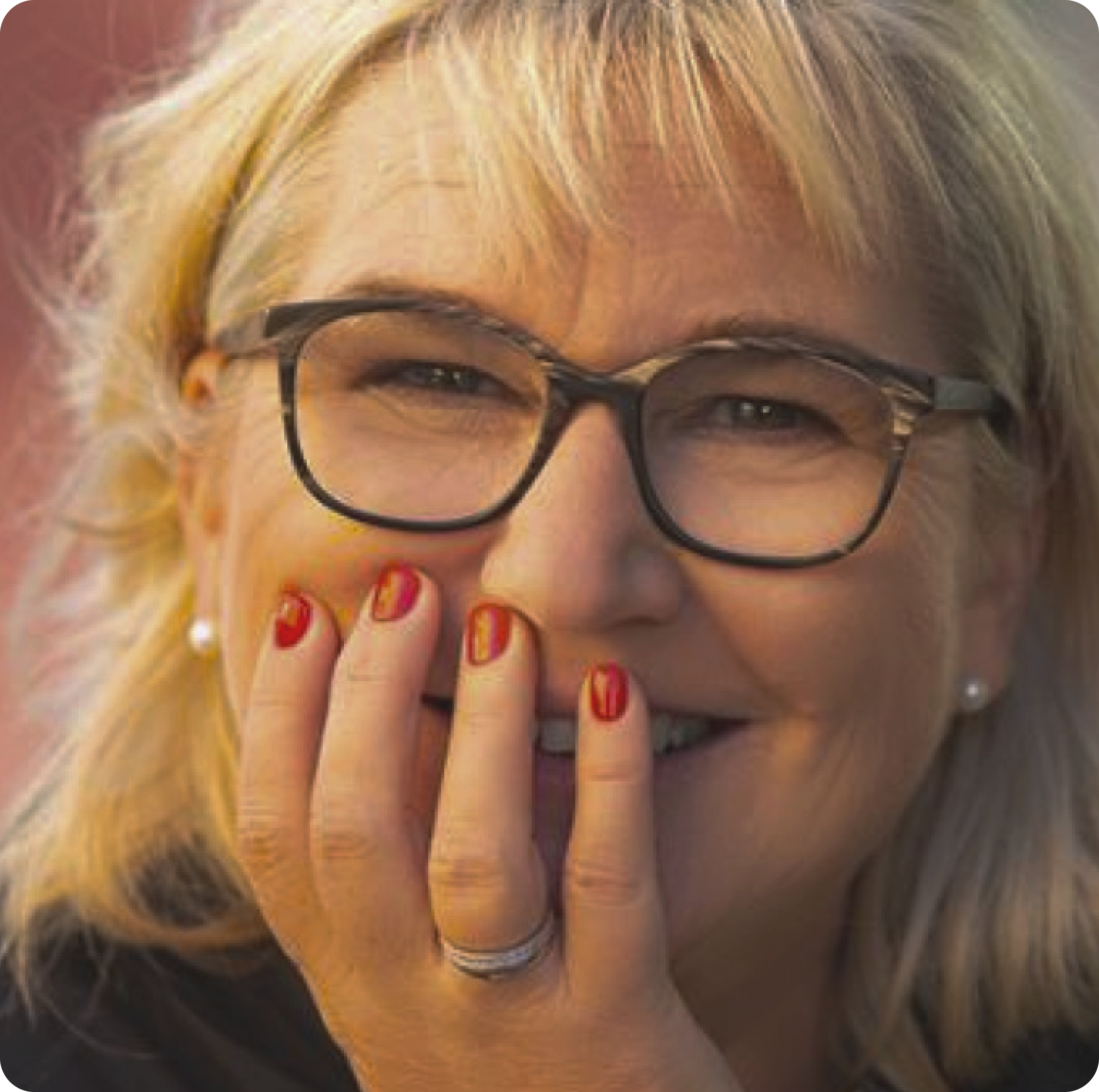 Eine Frau mit Brille lacht und hält sich dabei die Hand vors Gesicht